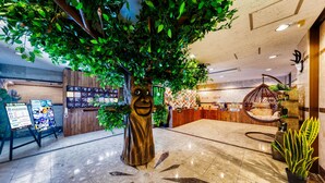 A lobby with a large artificial tree, a reception desk, and a seating area with a hanging chair. - Hotel Lotus morioka - Adult Only (Shizukuishi)