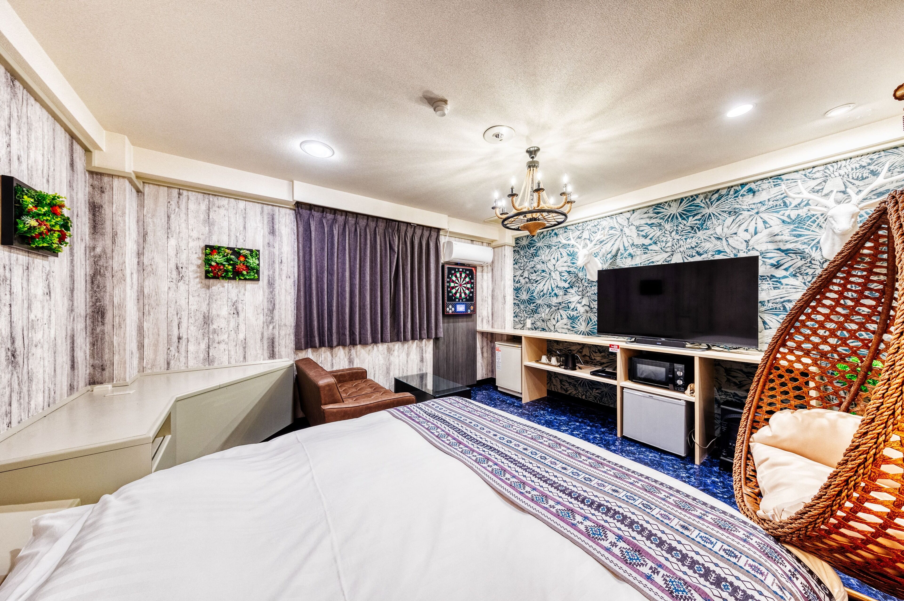 Una habitación de hotel moderna con cama, televisión, escritorio y una silla de mimbre.