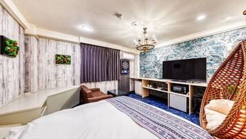 Una habitación de hotel moderna con cama, televisión, escritorio y una silla de mimbre.