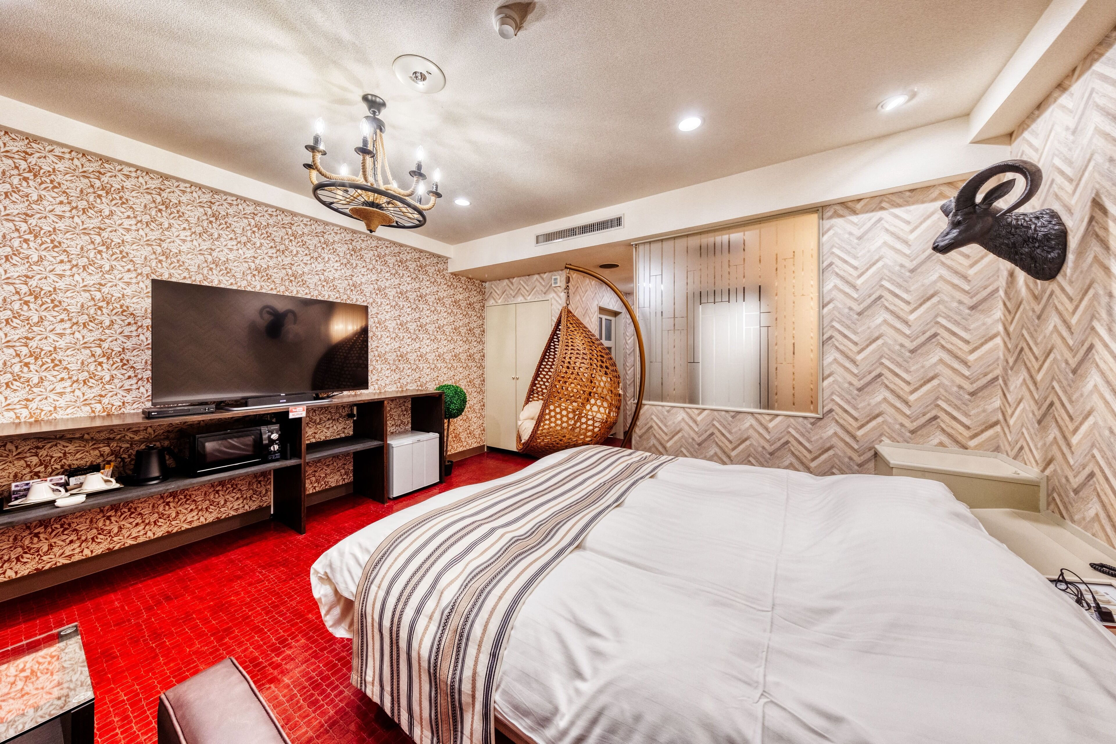 Una habitación de hotel moderna con una cama grande, un televisor, una silla colgante y una decoración en la pared.