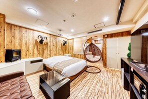 A modern bedroom with a wooden floor, a bed with a striped blanket, a hanging chair, a TV, and a small heater. - Hotel Lotus morioka - Adult Only (Shizukuishi)