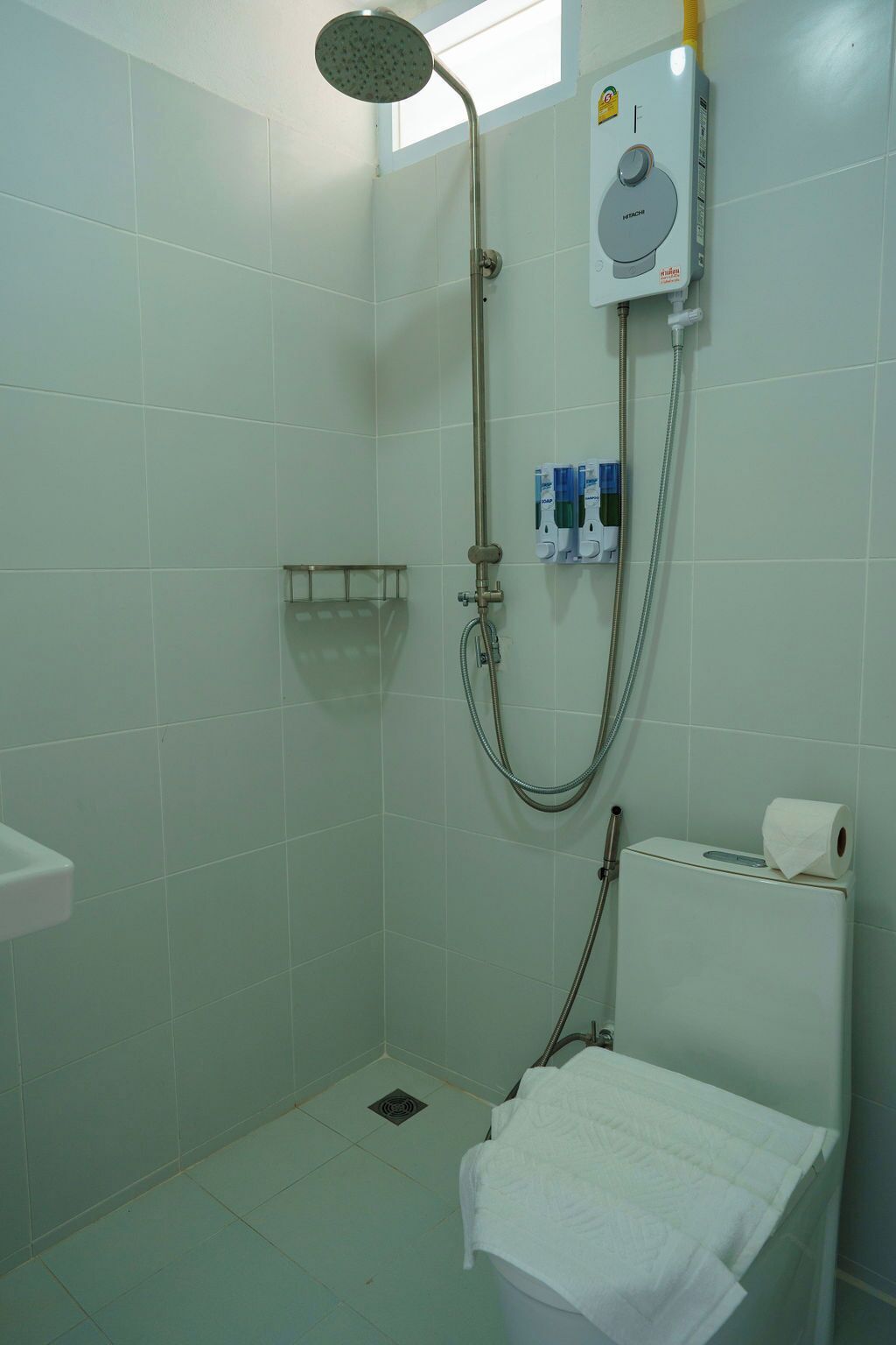 A small, clean shower area with a handheld showerhead, a toilet, and a towel rack.