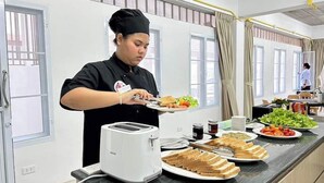 Una persona sirviendo comida en una cocina moderna con un ventanal grande, un tostador y varios platos en la encimera.