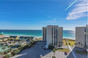 A beachfront hotel with multiple high-rise buildings, a parking lot, and a view of the ocean. - Beachside Bungalow (Destin)