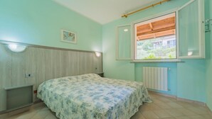 Et soveværelse med en seng, et vindue, en radiator og en vægmonteret lampe.