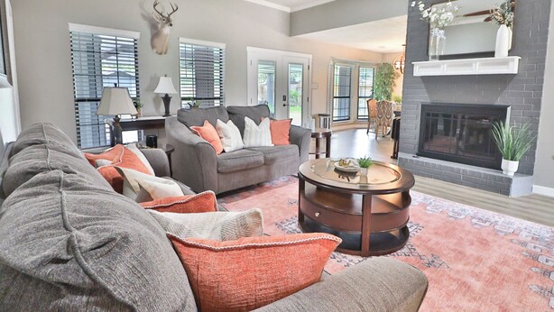 Ein Wohnzimmer mit grauem Sofa, einem runden Couchtisch und einem Kamin.