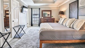 Ein Schlafzimmer mit einem Bett, einem Schminktisch, einem Spiegel, einem Deckenventilator und einem Fenster mit Vorhängen.