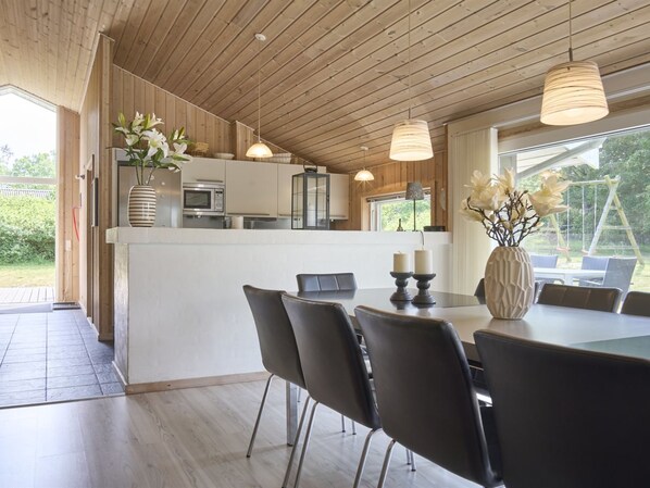 A modern kitchen with wooden ceiling, white cabinets, and a dining area with a table and chairs. - "Rudolf" - 400m from the sea by Interhome (Aakirkeby)