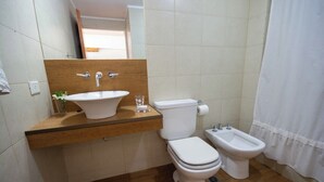 Ein Badezimmer mit einem Holzkosmetikschrank, einem Waschbecken, einer Toilette, einem Bidet und einer Duschkabine.