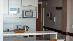 Eine moderne Küche mit weißen Schränken, einer Mikrowelle, einer Kaffeemaschine und einer Holtschale auf der Arbeitsfläche.