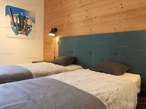 A bedroom with two beds, a wooden headboard, a wall-mounted lamp, and a poster. - Paradiski new, calm and sunny Plan peisey (PEISEY-NANCROIX)