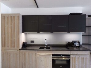 Una cocina moderna con armarios de madera, horno empotrado, cafetera y hervidor sobre la encimera.
