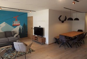 Una sala moderna con un sofá, una mesa de centro, un televisor y un comedor con sillas y una mesa.