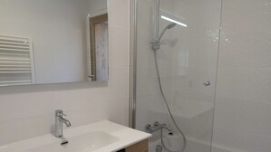 Ein modernes Badezimmer mit Waschbecken, Spiegel und einer Duschkabine.