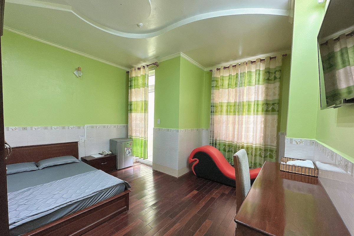 Ein Zimmer mit einem Bett, einem Schreibtisch, einem Stuhl, einem kleinen Tisch und einem Fernseher.