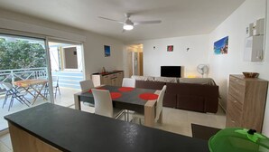 A modern kitchen with a dining area, a TV, and a balcony with a view. - Le Clos de l'Allamanda - Le Marin (LE MARIN)