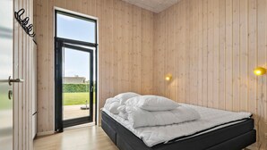 Een slaapkamer met een bed, houten wanden en een deur naar een balkon.