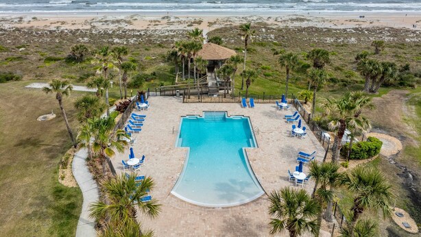 Ein Luftbild eines Resorts mit Schwimmbad, Strand und Palmen.