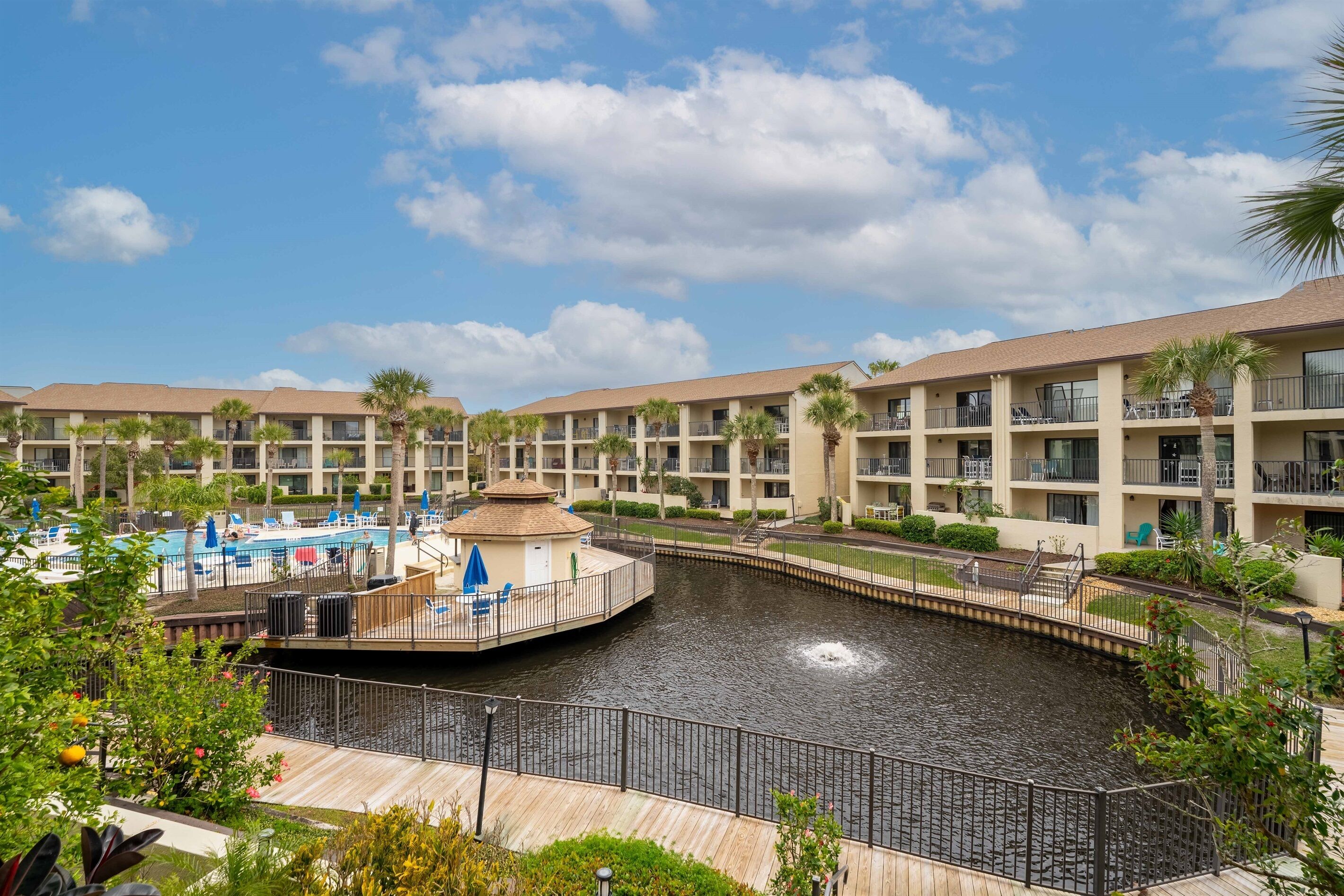 A hotel with a pool area, including a water feature and lounge chairs.