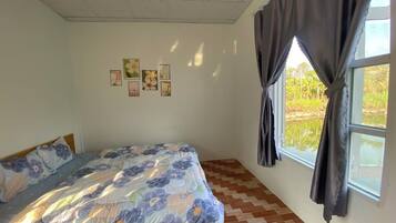 A bedroom with a bed, a window with curtains, and wall-mounted pictures.
