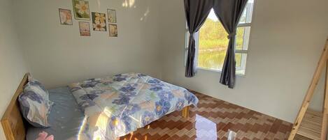 A bedroom with a bed, a window with curtains, a wooden ladder, and a herringbone-patterned floor.