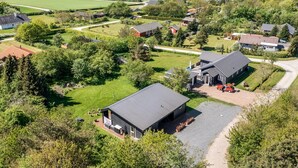 A modern house with a large garage, surrounded by lush greenery and a view of the sea. - "Melina" - 900m to the fjord by Interhome (Farsø)