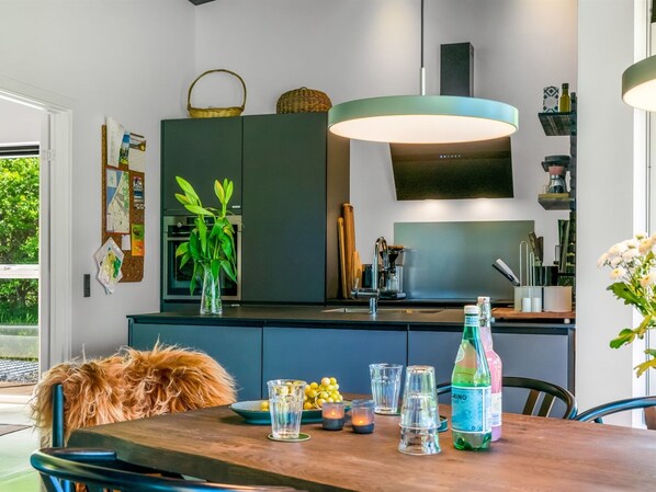 A modern kitchen with dark cabinetry, a central island, and a hanging light fixture.