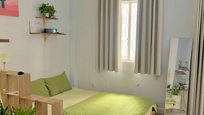 A bedroom with a bed, a wooden nightstand, a mirror, and a window with curtains. - TRIP HOME 2 (Ho Chi Minh City)