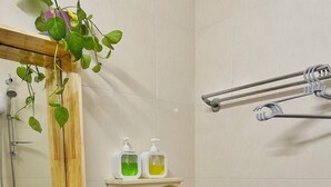 A bathroom with a sink, toilet, and shower. There is a shelf with soap dispensers and a hanging plant. - TRIP HOME 2 (Ho Chi Minh City)