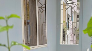 A balcony with wooden furniture, potted plants, and a view of buildings in the background. - TRIP HOME 2 (Ho Chi Minh City)