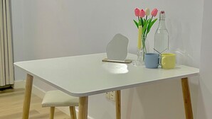 A white table with a glass vase containing pink and white tulips, a clear bottle, and two mugs. - TRIP HOME 2 (Ho Chi Minh City)