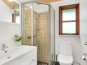 Une salle de bain équipée d’une douche, de toilettes, d’un lavabo et d’une fenêtre.