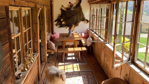 Een rustiek interieur met houten wanden, een eethoek en een groot raam met uitzicht op de omgeving.
