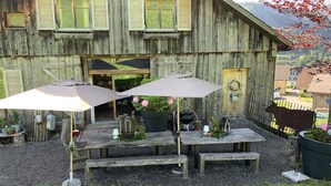 Een rustiek houten gebouw met een overdekt terras, voorzien van zitplaatsen en parasols.