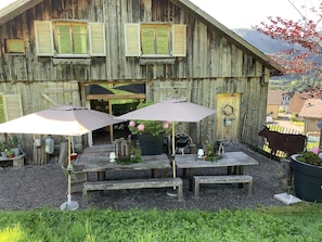 Ein rustikales Holzgebäude mit überdachter Terrasse, Sitzmöglichkeiten und Sonnenschirmen.