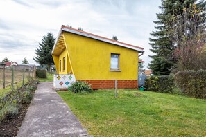 Et gult hus med rødt tag, et lille vindue og en støbt sti, der fører hen til det.