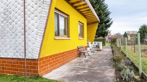 Un edificio amarillo con base de ladrillo, una banca afuera y un sendero pavimentado.