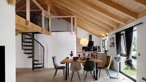 A dining area with a wooden table, chairs, a spiral staircase, and a view of the outdoors. - Holiday Apartment 'Ferienoase Im Land Der 1000 Seen' with Private Terrace, Shared Garden & Wi-Fi (Karstädt)
