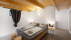 A bedroom with a wooden ceiling, a bed with two pillows, a bedside table with a lamp, and a wall-mounted light fixture. - Holiday Apartment 'Ferienoase Im Land Der 1000 Seen' with Private Terrace, Shared Garden & Wi-Fi (Karstädt)