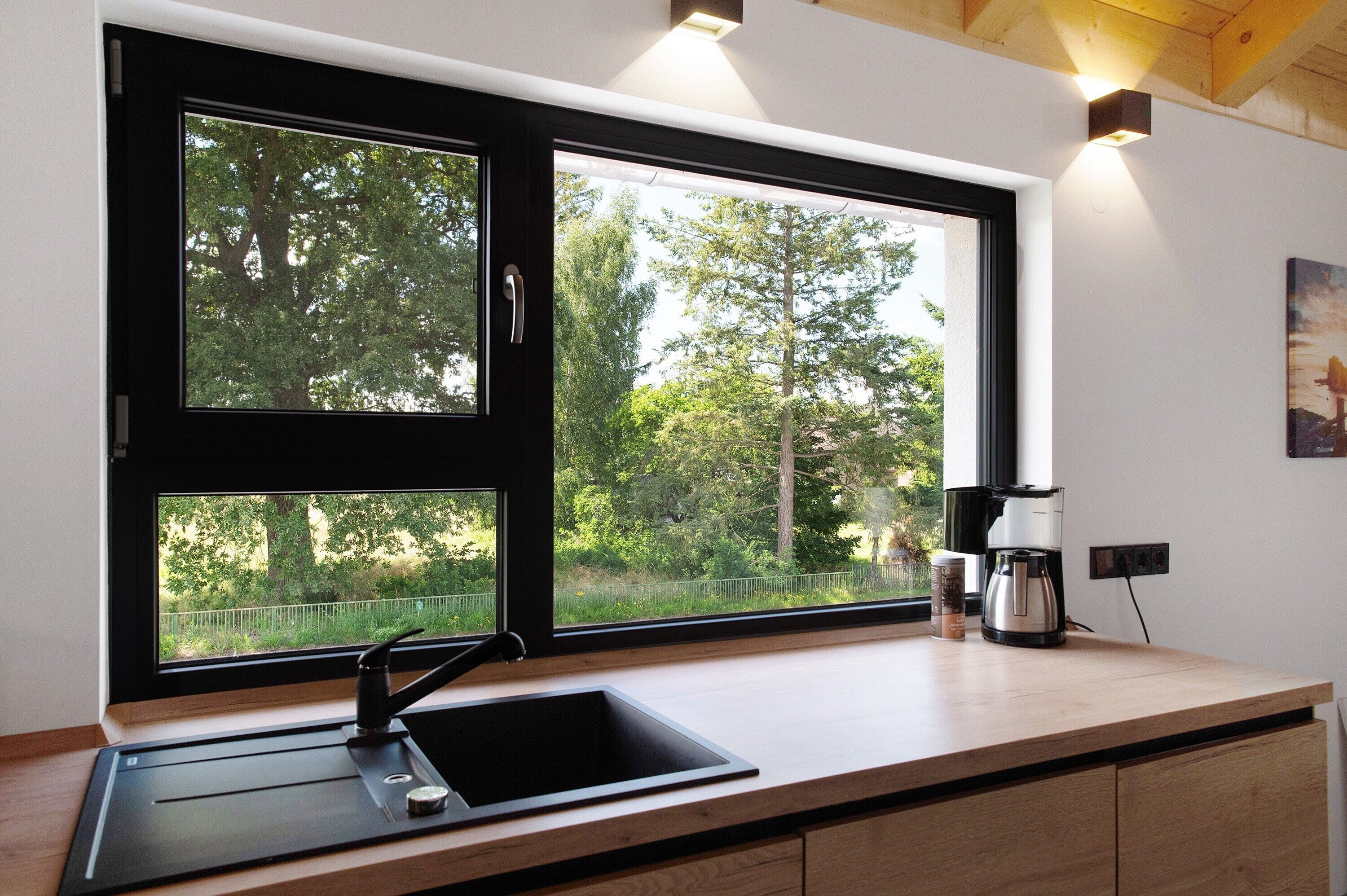Eine Küche mit großem Fenster, Spüle und Kaffeemaschine.