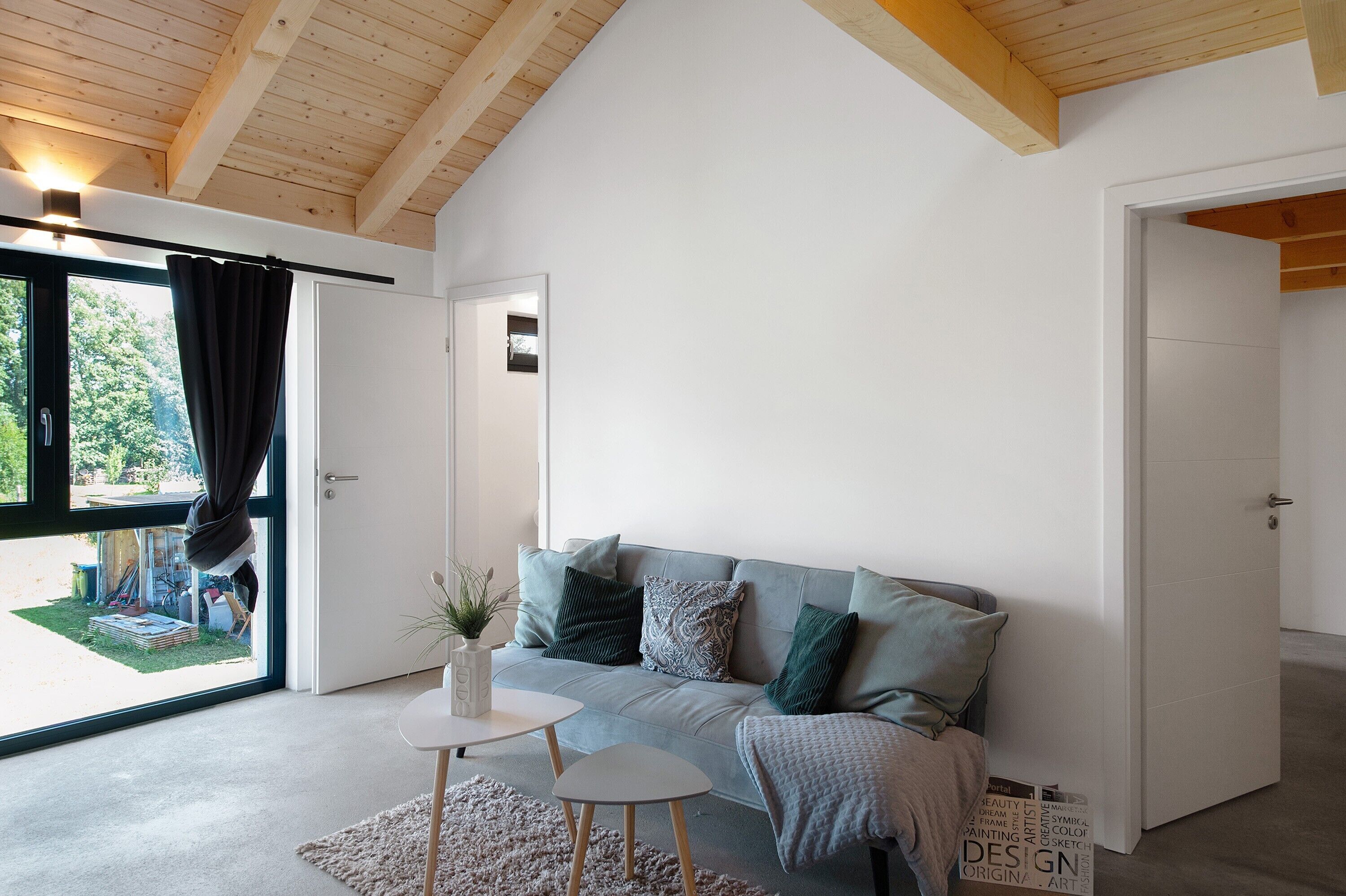 A modern interior with a grey sofa, a small round table, and a white door leading outside.