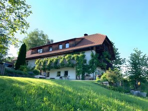 Une maison à deux étages, dotée d’un toit en pente, entourée d’une pelouse bien entretenue et de verdure.
