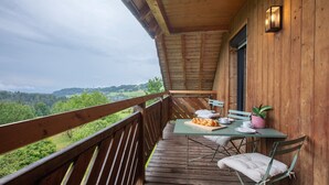 Ein hölzerner Balkon mit einem Tisch für zwei Personen, einem Stuhl und einem Blumentopf.