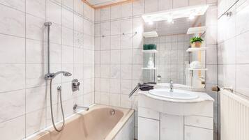 A bathroom with a bathtub, a sink, and a mirror.