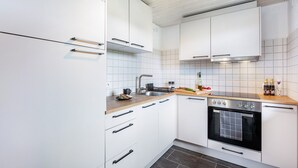 A modern kitchen with white cabinets, a stainless steel sink, and a built-in oven. - Holiday Apartment 'Käppeleblick' with Mountain View, Private Terrace and Wi-Fi (Bernau im Schwarzwald)