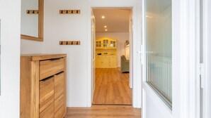 A hallway leading to a kitchen with wooden cabinets and a mirror on the wall. - Apartment 'Ferienhof Paulsen - Seeschwalbe' with Private Terrace and Wi-Fi (Pellworm)