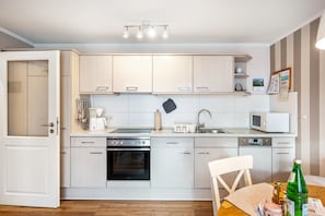 Une cuisine moderne avec des meubles de couleur bois clair, un four encastré, un four à micro-ondes et un évier.