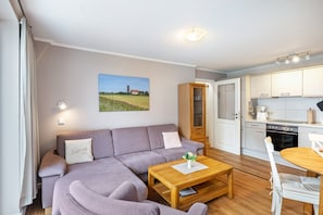 En moderne stue med sofa, sofabord i træ og spisebord med stole.