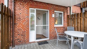 Un patio con tavolo e sedie, una recinzione in legno e un muro in mattoni.