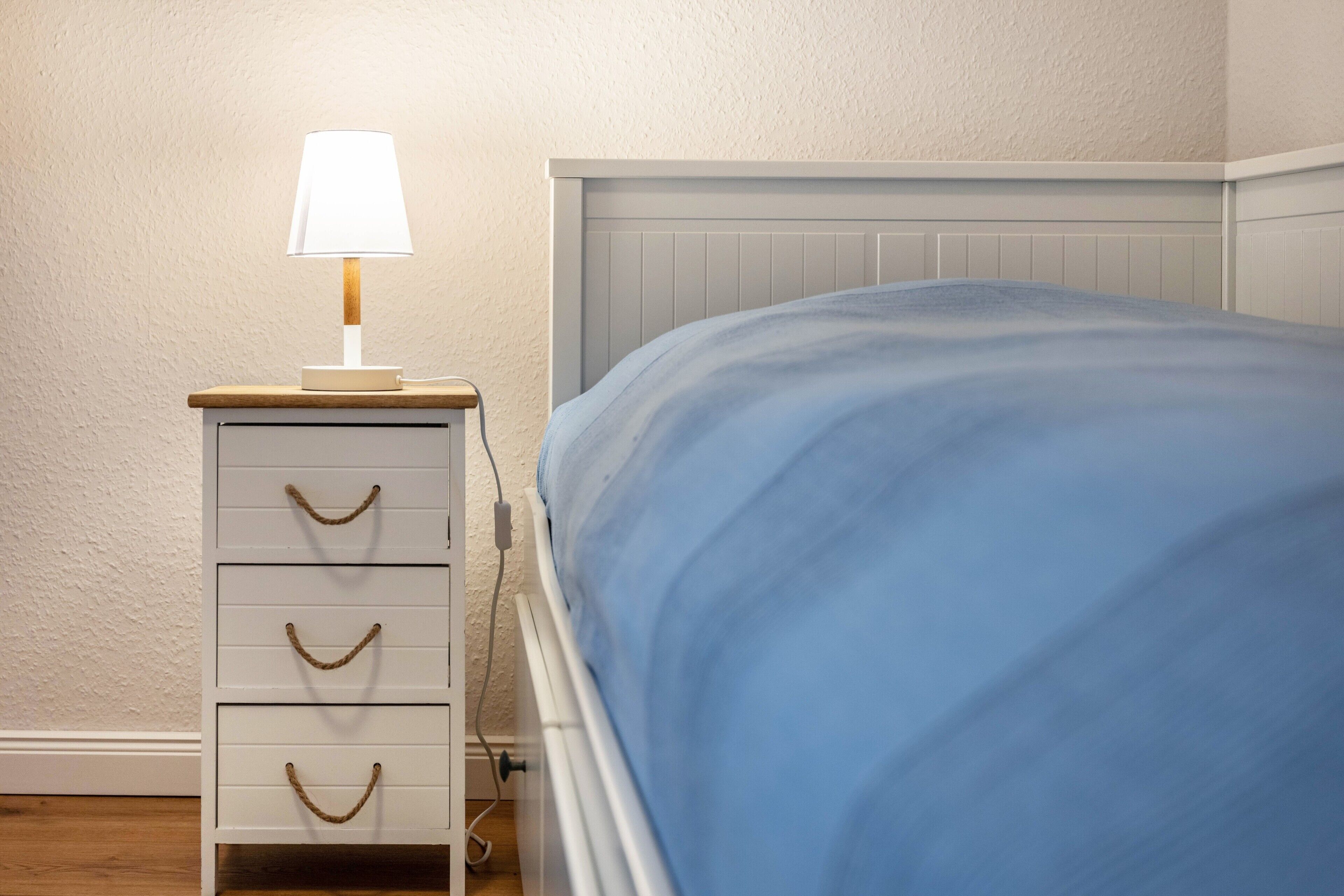 Une chambre à coucher avec un lit, une table de chevet avec une lampe et une commode.